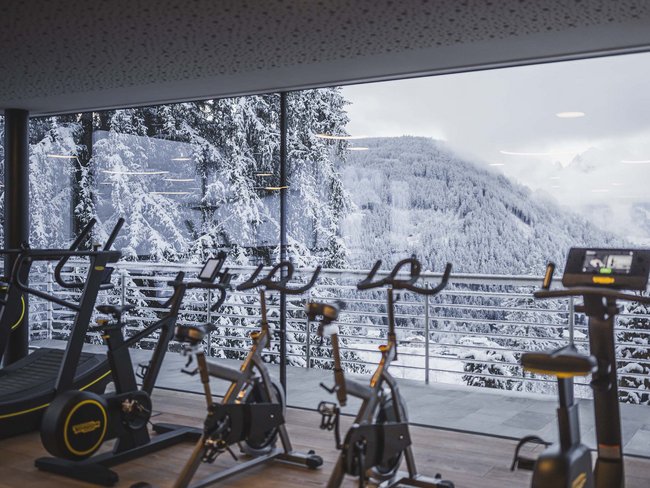 Fitnessraum mit Heimtrainern und Winterlandschaft durch große Fenster
