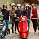 Sechs Personen in Motorradhelmen mit drei unterschiedlichen farbigen Vespa-Rollern