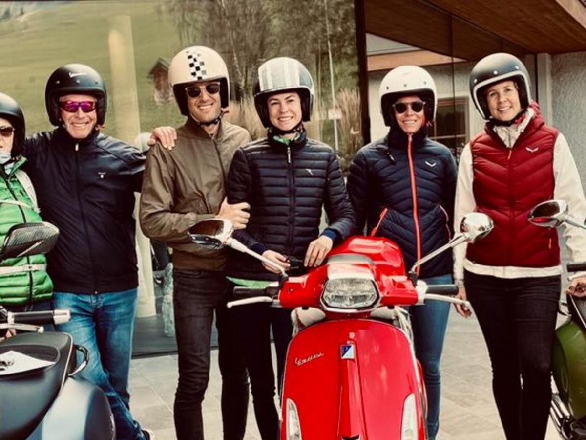 Sechs Personen in Motorradhelmen mit drei unterschiedlichen farbigen Vespa-Rollern