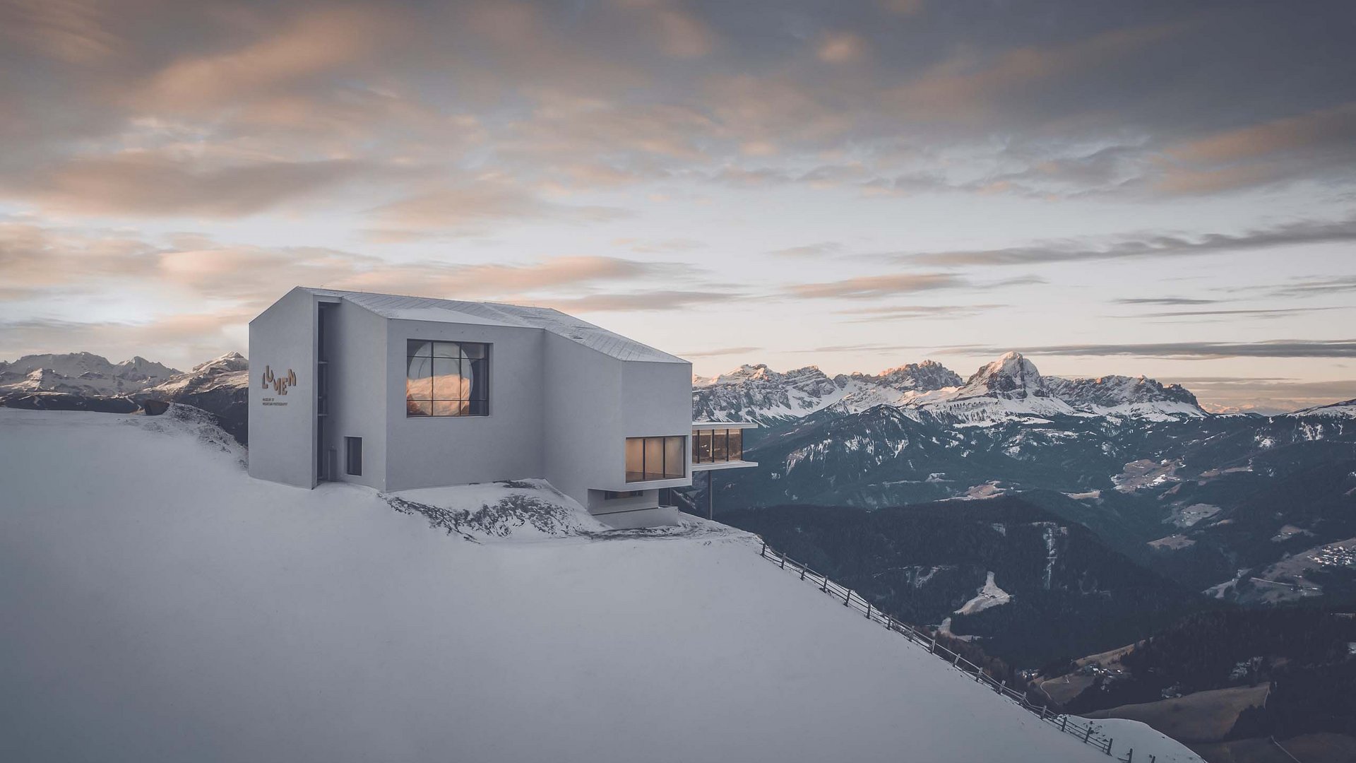 Modern building on snowy mountain with alpine panorama in the background
