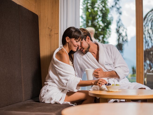 Alpen Tesitin: Ihr Wellnesshotel im Pustertal Paar in Bademänteln genießt Obst und Kaffee in einem gemütlichen Spa-Bereich