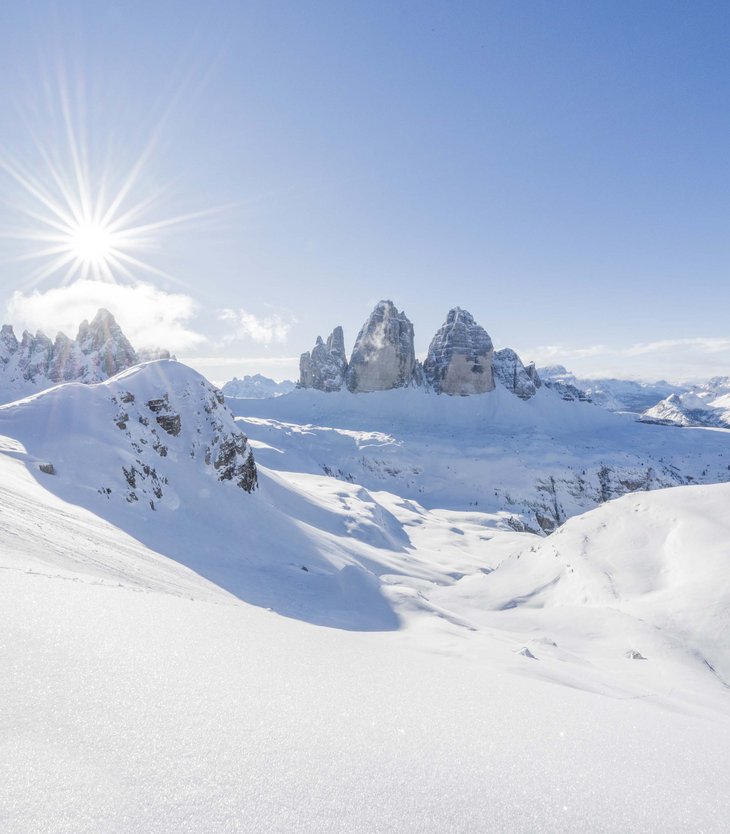 5-Sterne-Sporthotel in Südtirol gesucht? Sonnige Winterlandschaft mit schneebedeckten Bergen und klar blauem Himmel