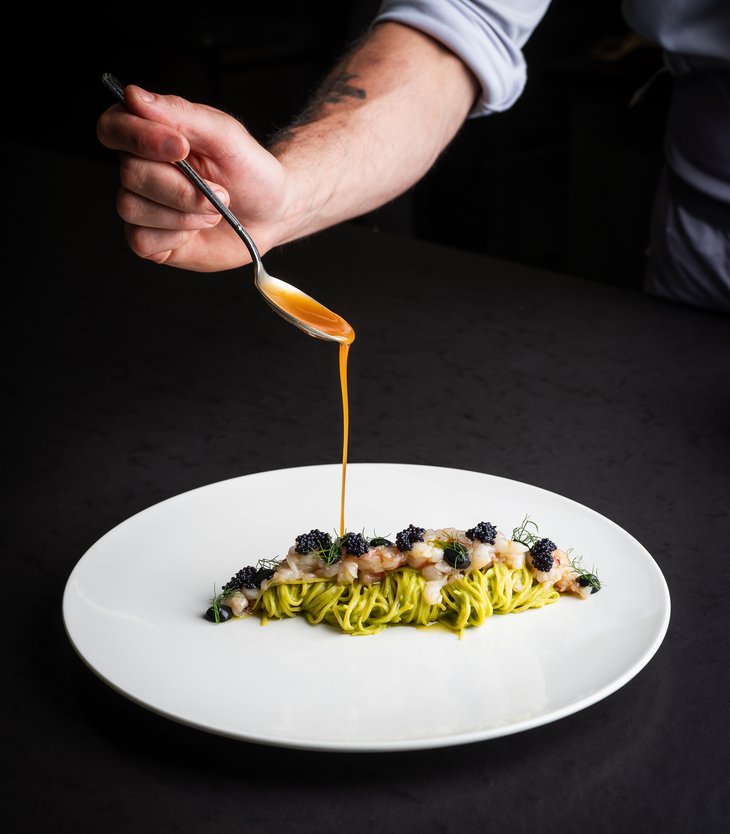 Your 5-star hotel in Val Pusteria/Pustertal: Alpen Tesitin A chef pouring sauce over artfully plated pasta with seafood and caviar.
