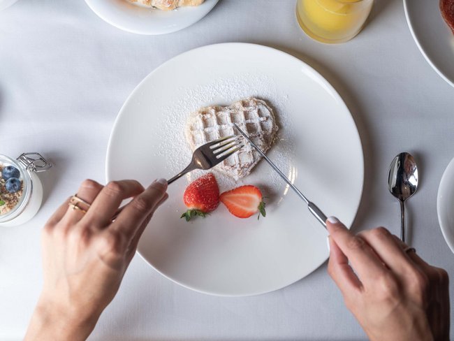Herzförmige Waffel mit Puderzucker und Erdbeeren auf weißem Teller
