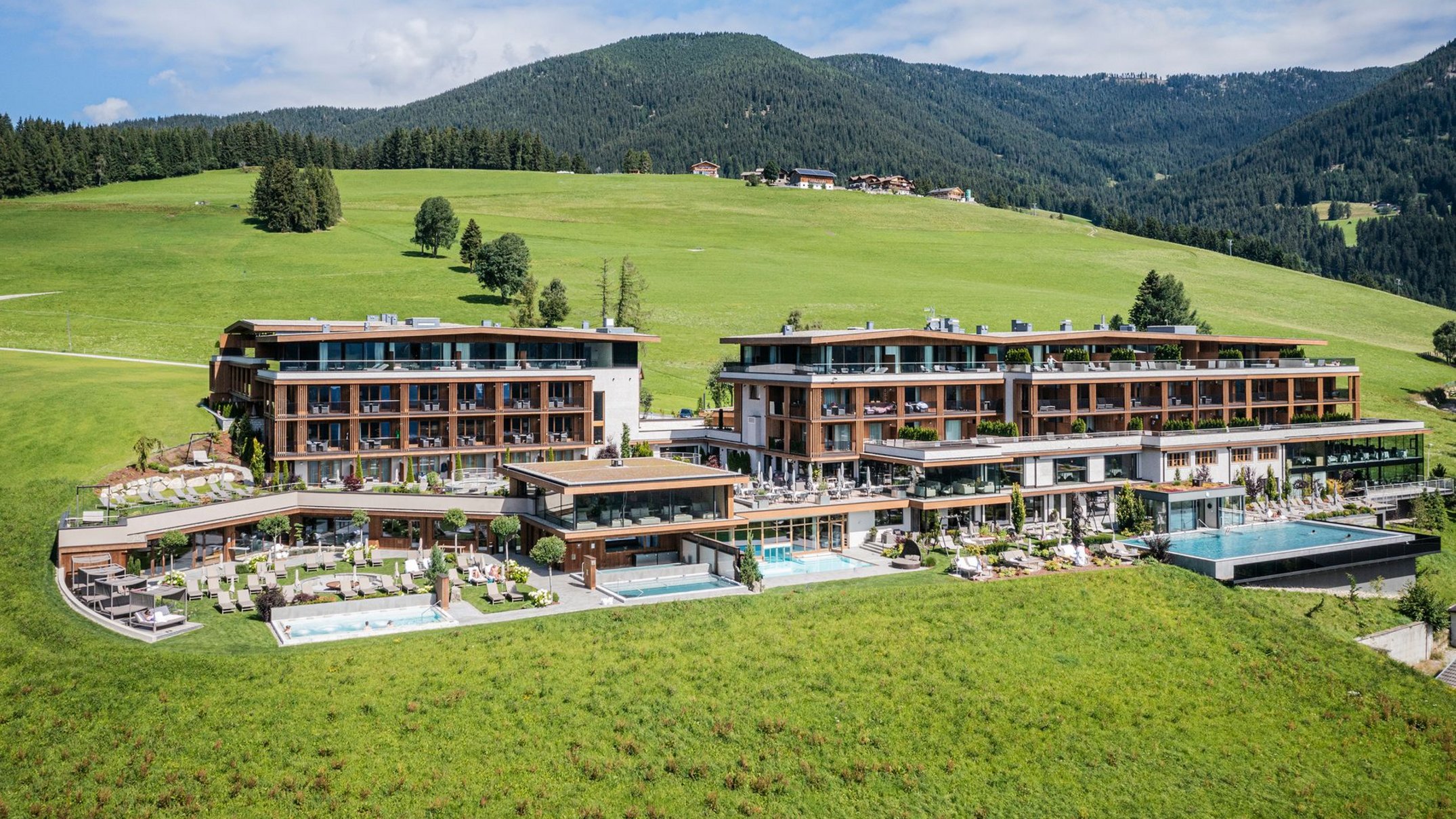 Alpen Tesitin: una storia da raccontare Hotel moderno con piscine esterne in paesaggio montano verde