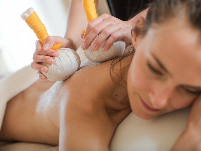 Woman receiving herbal compress massage on her back