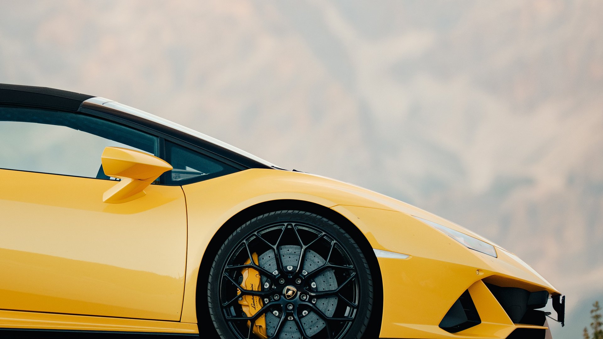 Seitenansicht eines gelben Sportwagens vor verschwommenen Bergen