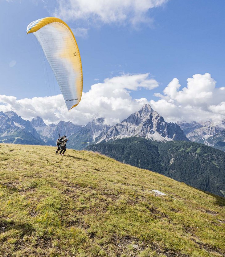 Persone che si preparano al decollo con parapendio su una collina soleggiata