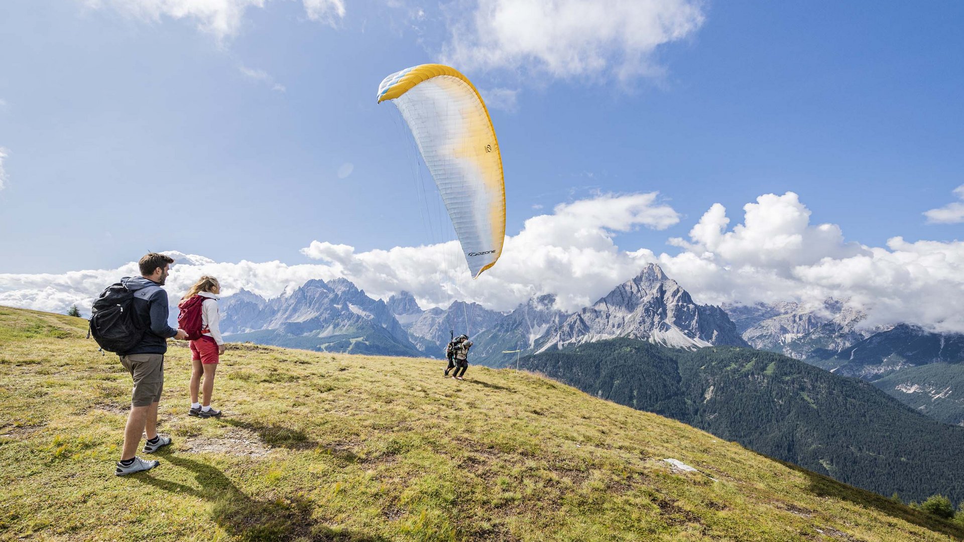 Persone che si preparano al decollo con parapendio su una collina soleggiata
