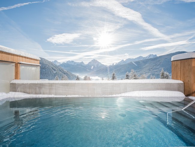 Outdoor-Pool bei Schnee mit Bergblick unter sonnigem Himmel