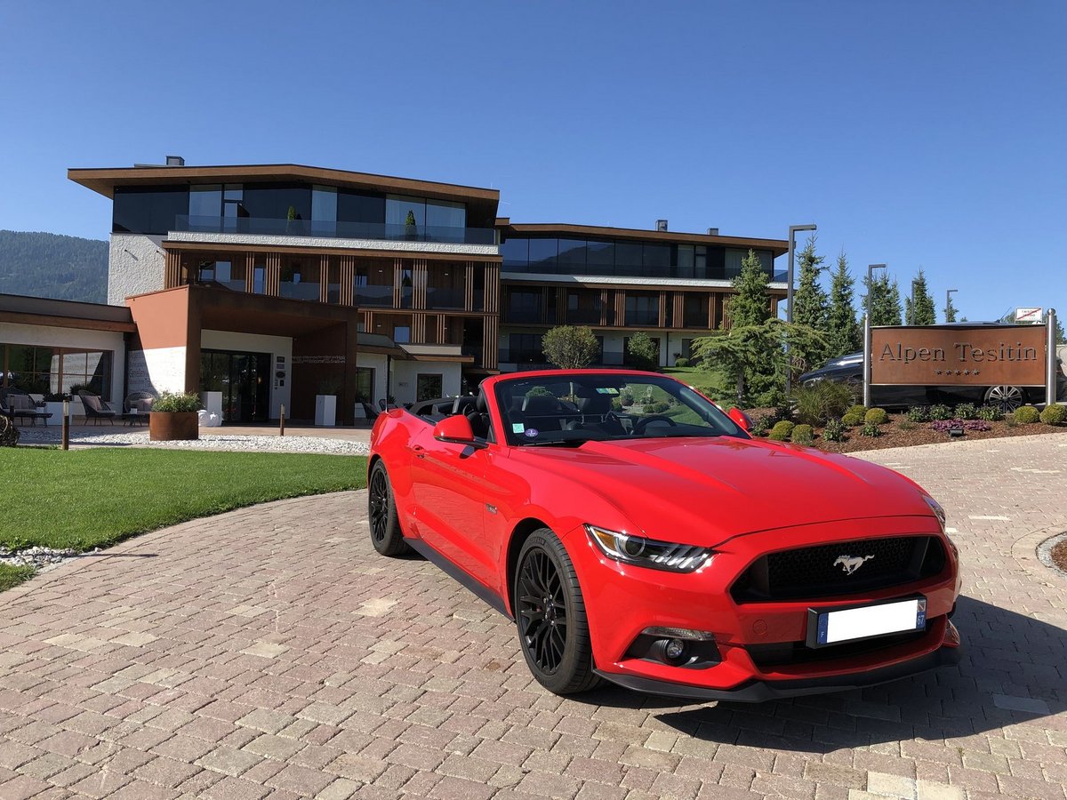 Alpen Tesitin: Here’s what our guests have to say. Red Ford Mustang convertible parked in front of Alpen Tesitin hotel on sunny day
