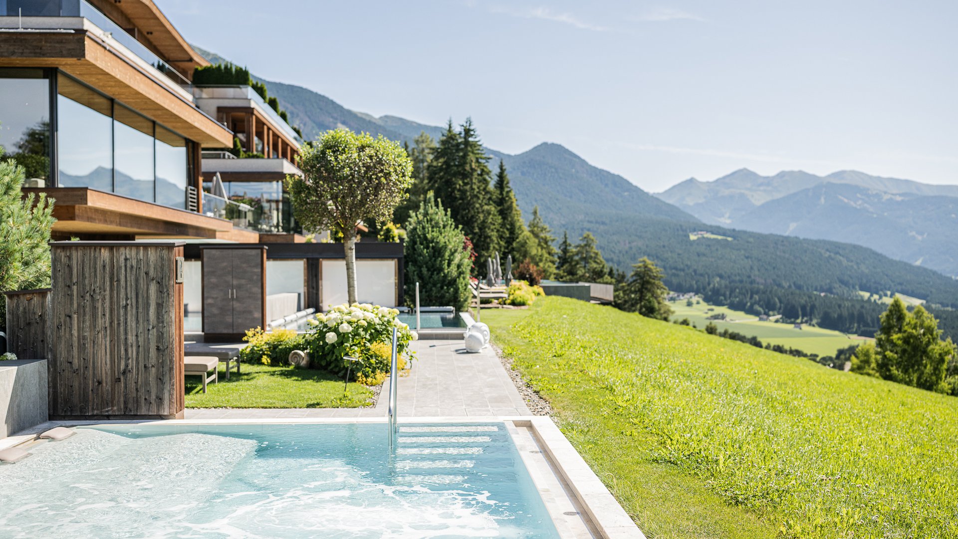 Hotel con sauna in Alto Adige:l’Alpen Tesitin Piscina esterna e suite d'hotel moderna con vista sulle montagne e valle verde