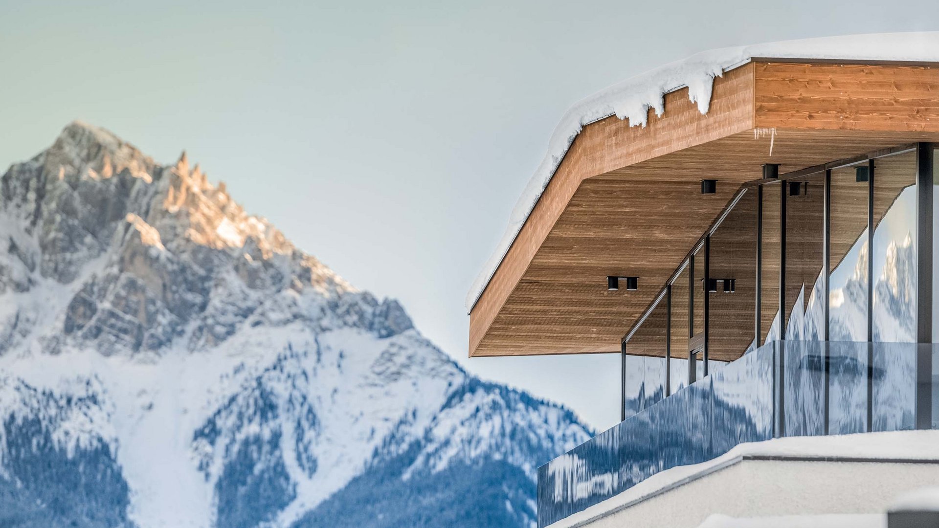 Spontanurlaub im Pustertal Moderne Hütte mit Holzfassade und Glasgeländer vor verschneitem Berg