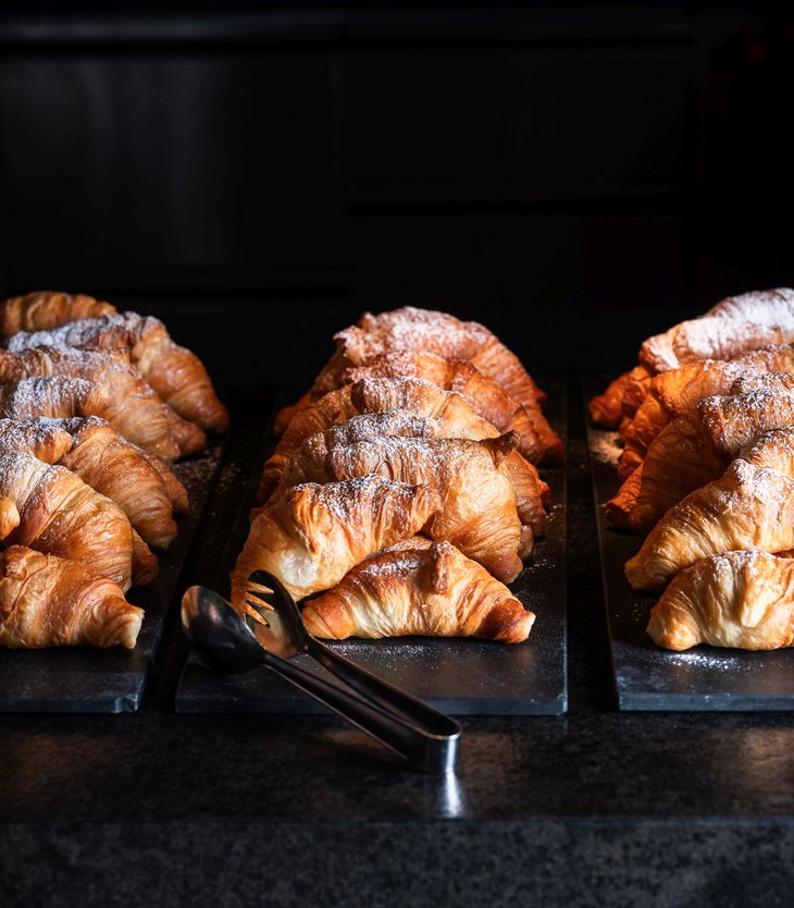 Alpen Tesitin: Ihr Gourmethotel in Südtirol Frisch gebackene Croissants auf schwarzen Platten mit Zucker bestreut