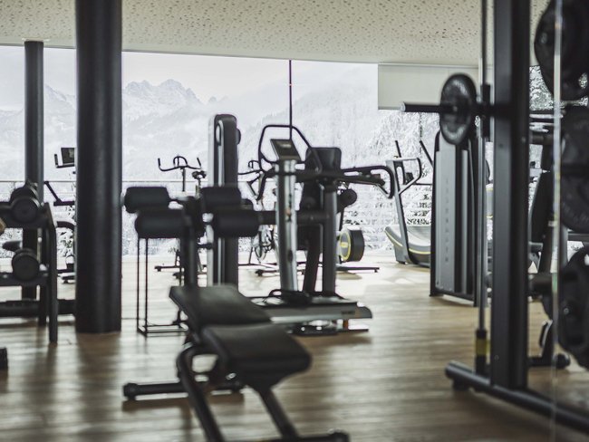 Trainingsgeräte in einem Fitnessstudio mit Blick auf verschneite Berge