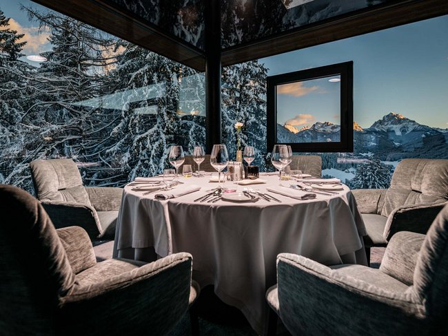 Sala da pranzo elegante con tavolo rotondo e vista sulle montagne innevate
