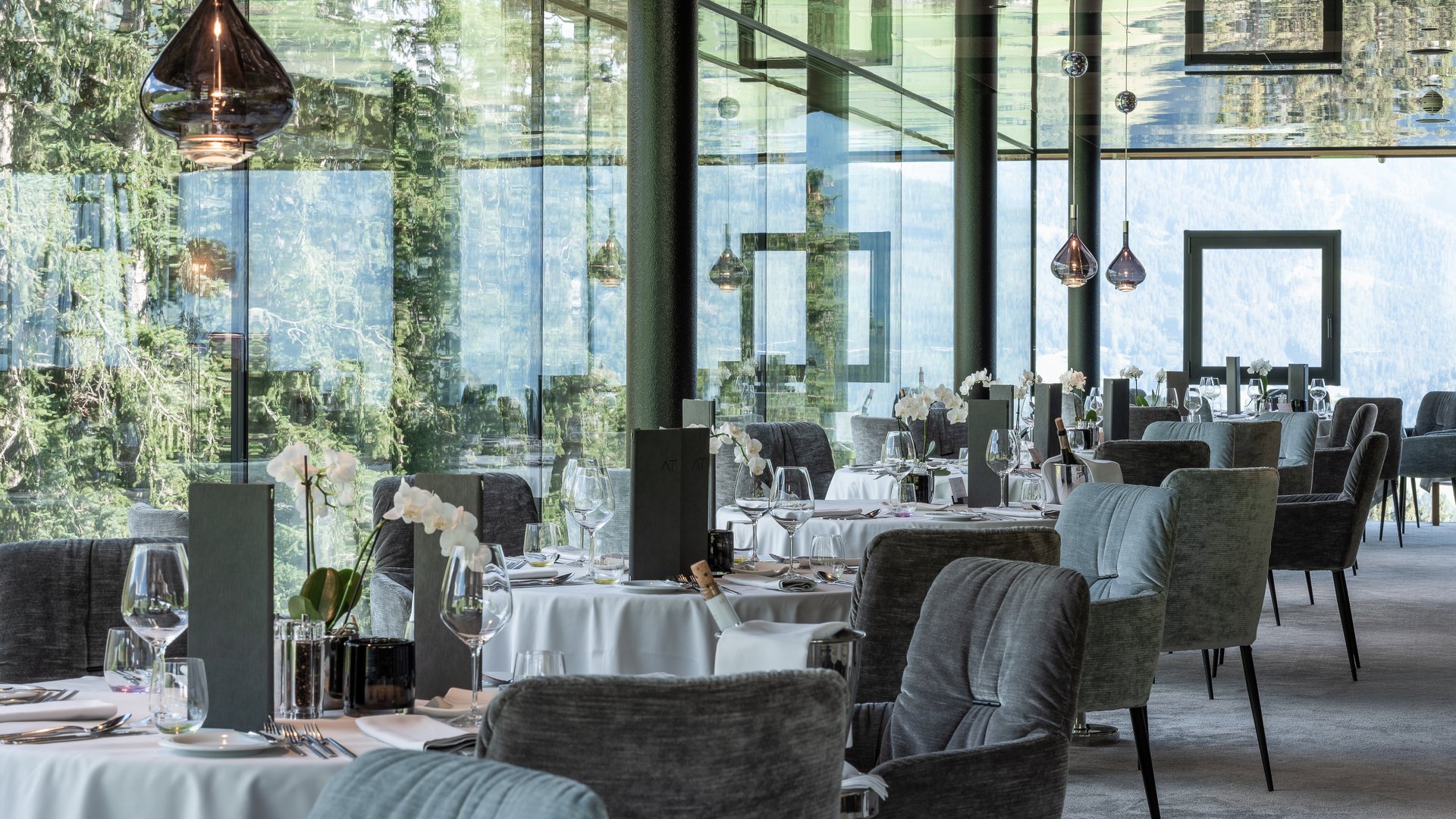 Elegantes Restaurant mit Glaswänden und gedeckten Tischen mit weißen Tischdecken