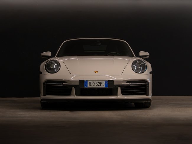 Front view of a white Porsche sports car against a dark background