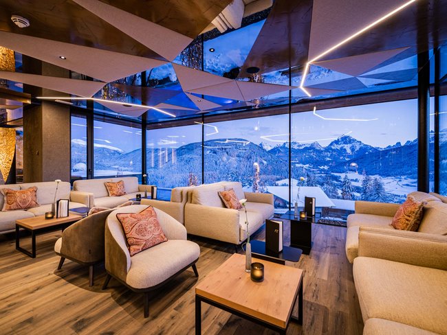Urlaub im Hotel in den Dolomiten Gemütlicher Lounge-Bereich mit Panoramablick auf verschneite Berge