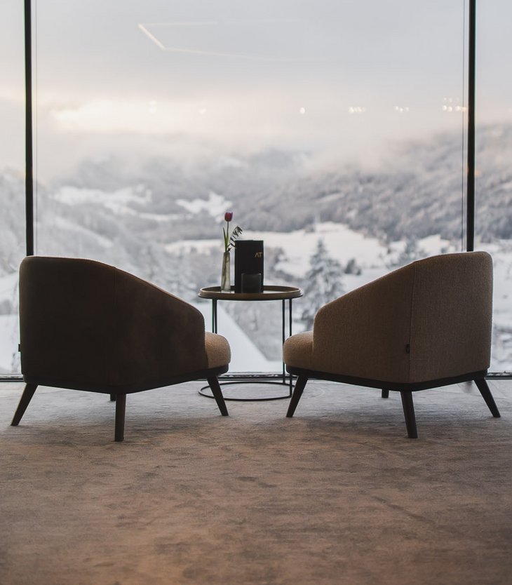 Moderne Lounge mit Blick auf schneebedeckte Berglandschaft durch große Fenster