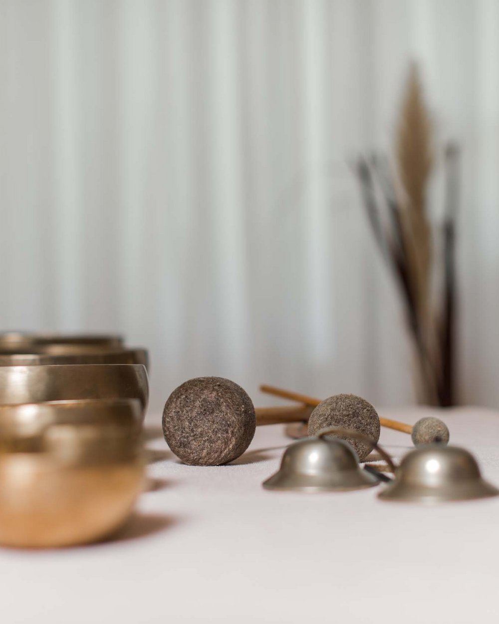 Treatments im Alpen Tesitin Meditationsglocken und Klangschalen auf einem Tisch mit weichem Hintergrund