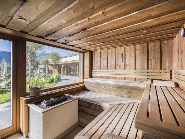 Interno di una sauna con panche in legno e vista esterna dal finestrone