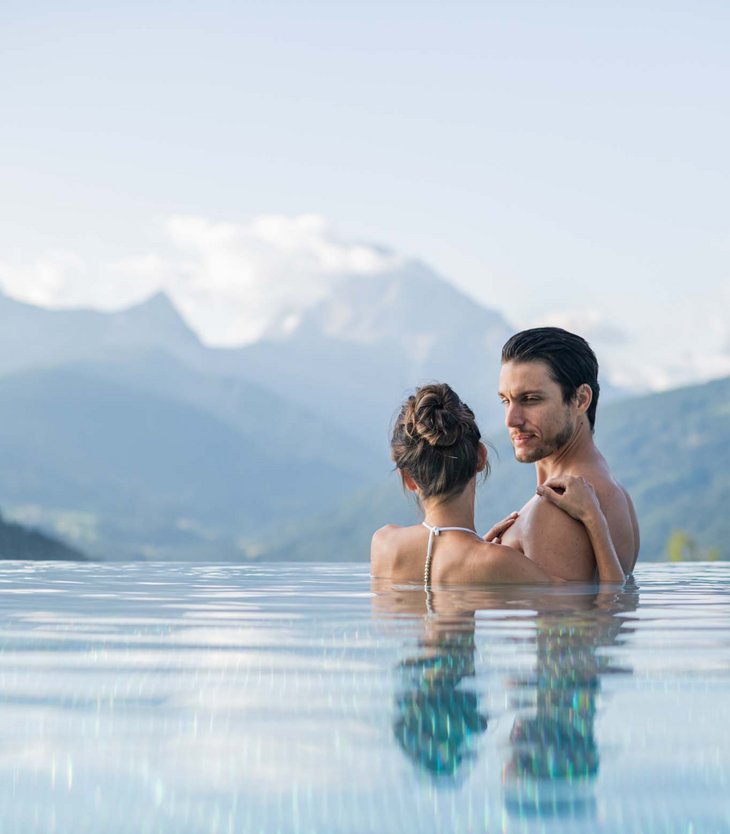 Couple embracing in infinity pool with mountains in the background