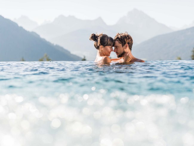 Pärchen genießt Zeit in Infinity-Pool mit Bergpanorama