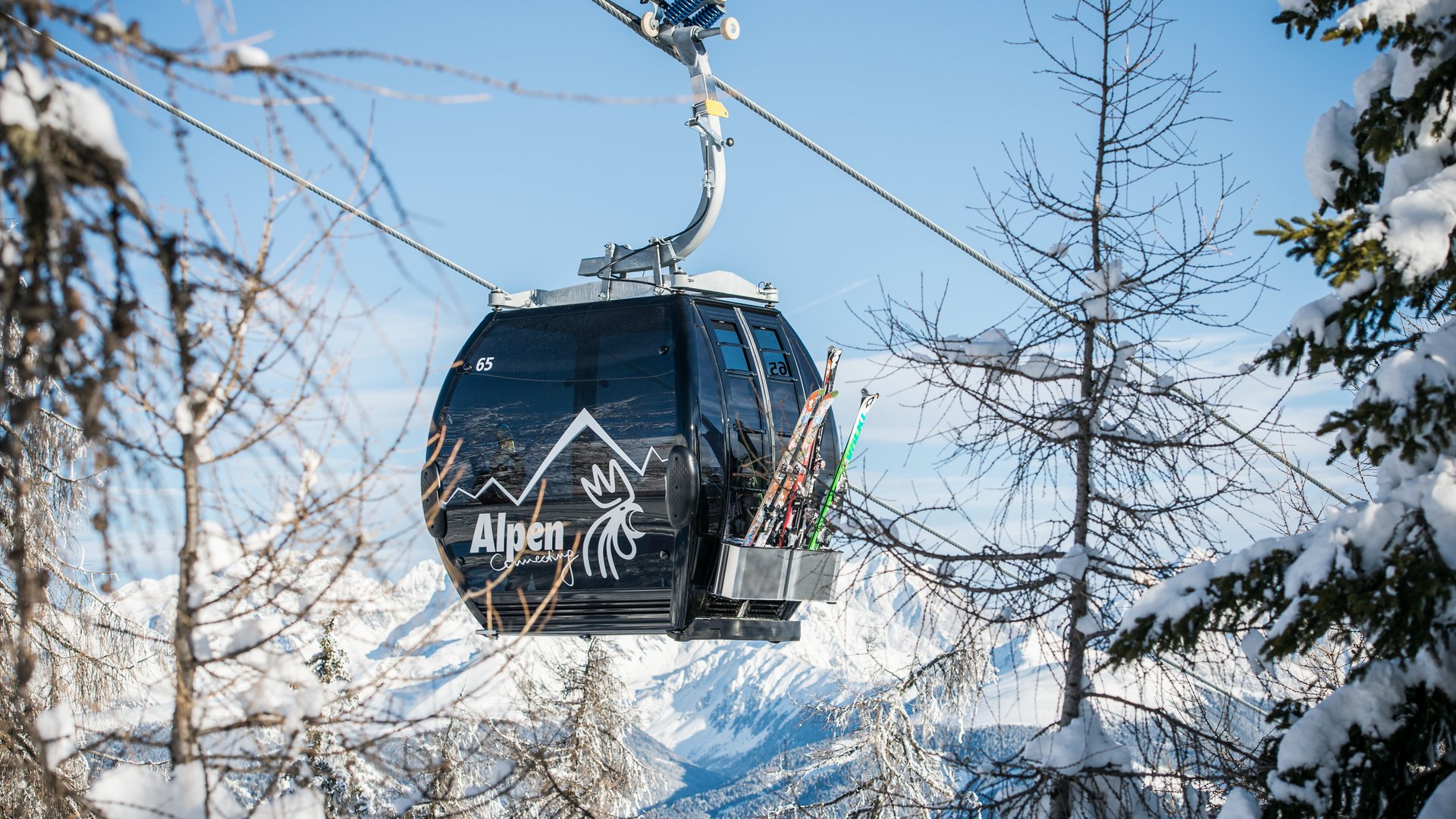 Cabina funivia nera tra alberi innevati con sci montati all'esterno