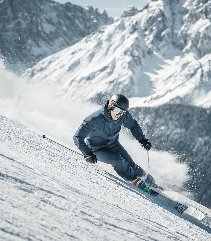 Skifahrer fährt auf schneebedecktem Berghang mit Bergen im Hintergrund