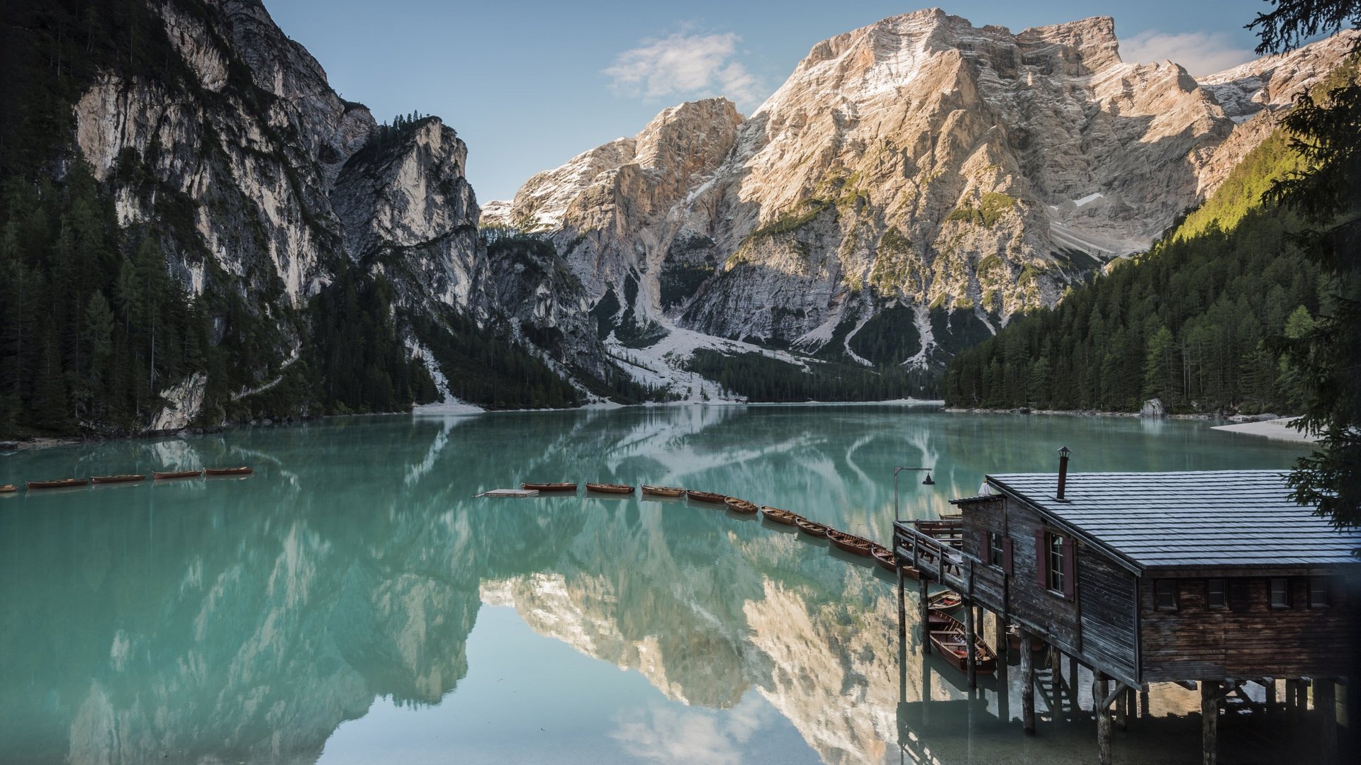 Bergsee mit Bootssteg und reflektierenden Bergen im klaren Wasser