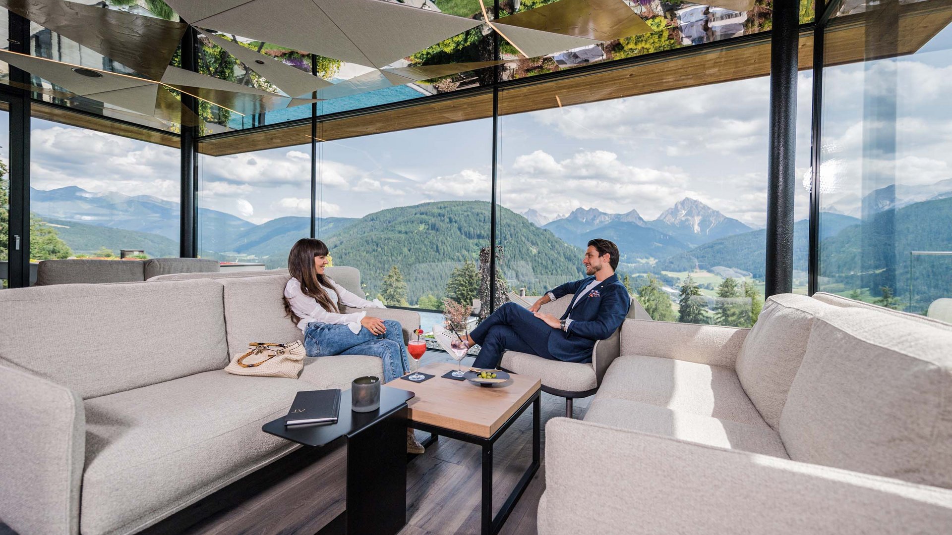 Two people sitting in a modern room with panoramic mountain views
