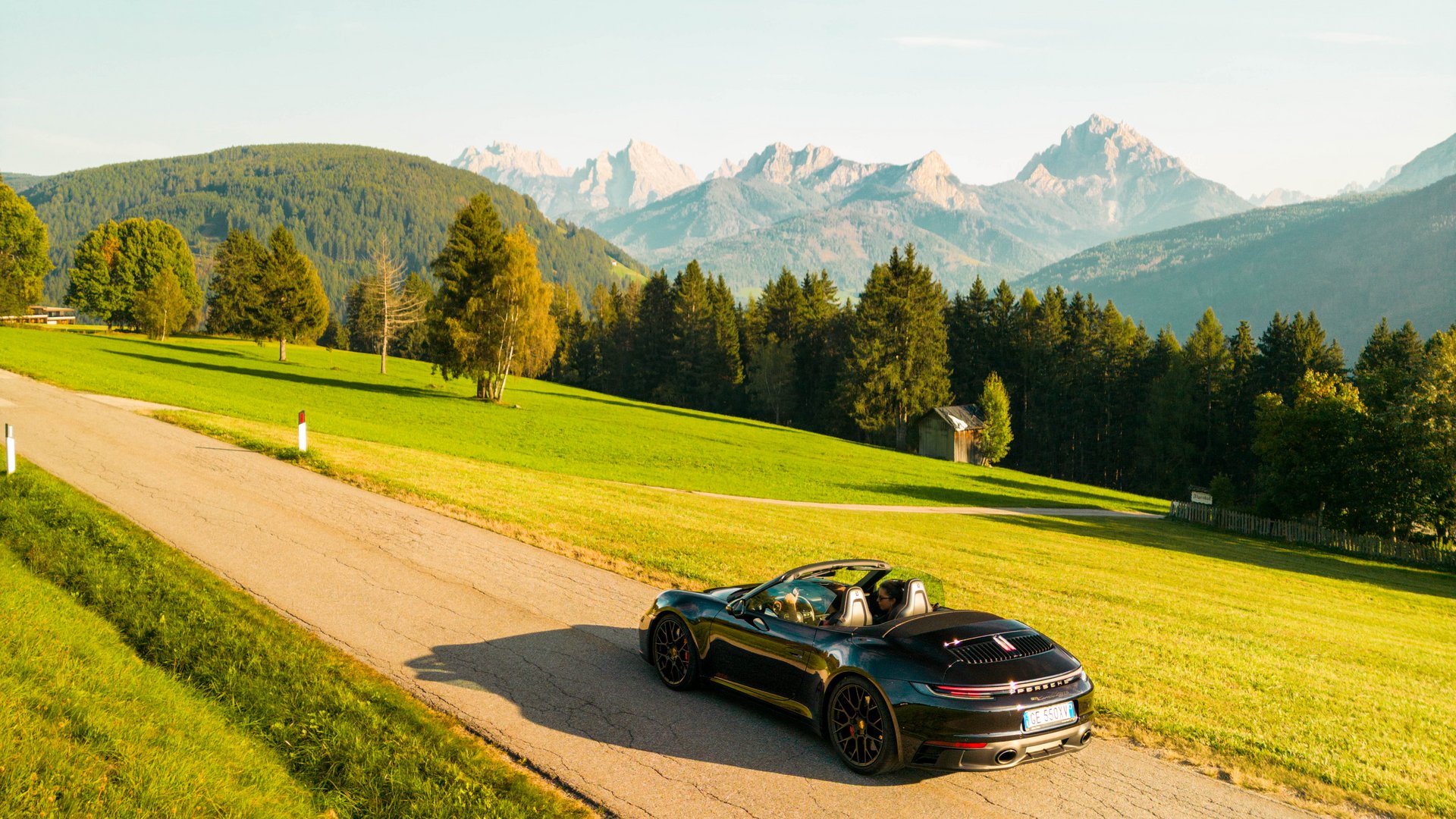 Black convertible sports car on rural road with mountains in the background