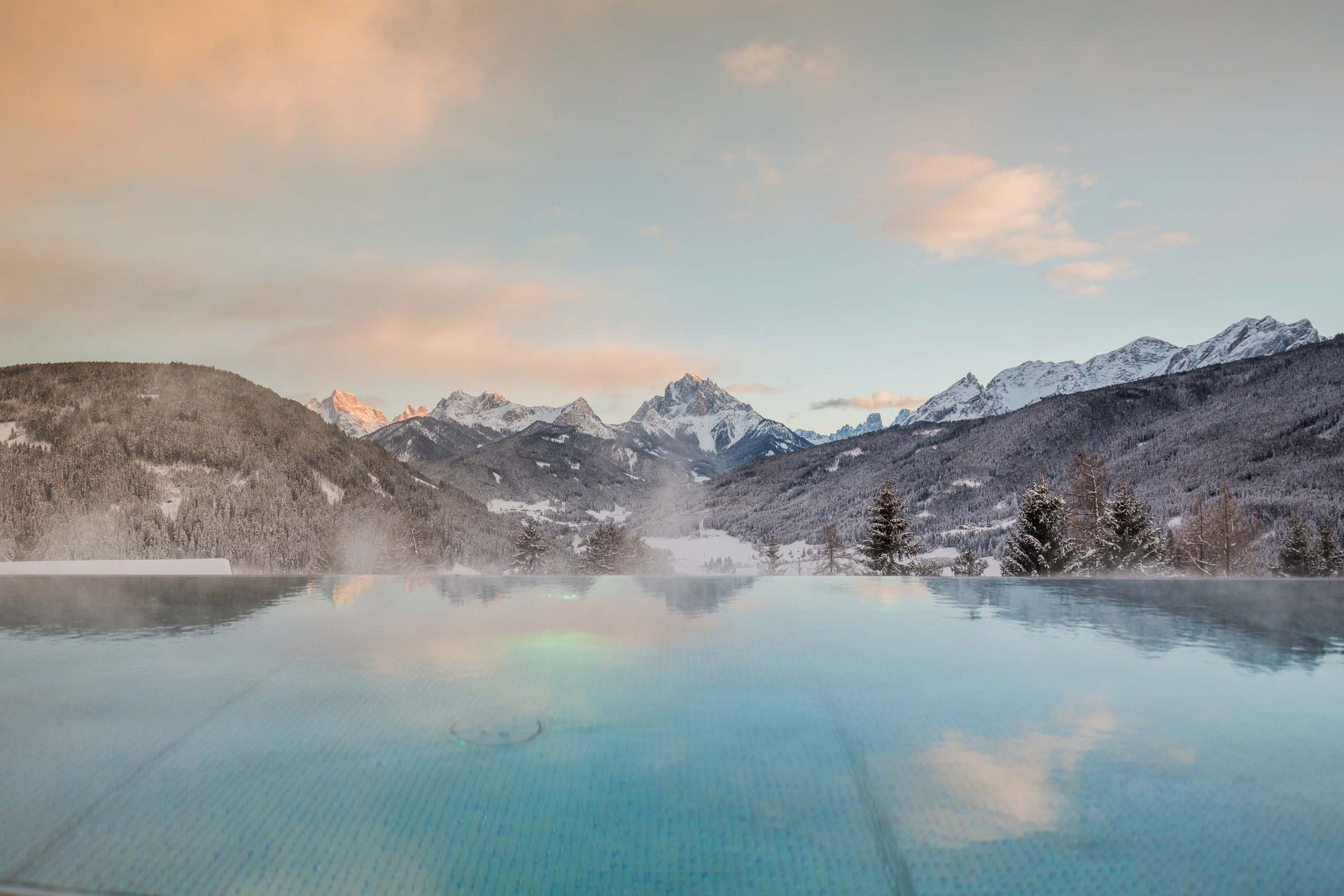 Un family hotel in Val Pusteria: straordinario! Piscina riscaldata con vista sulle montagne innevate al tramonto
