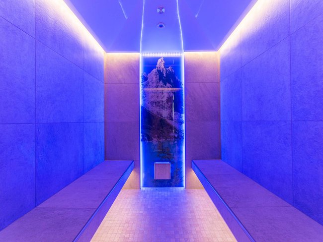 Stanza moderna con illuminazione blu e immagine di montagne su pannello retroilluminato