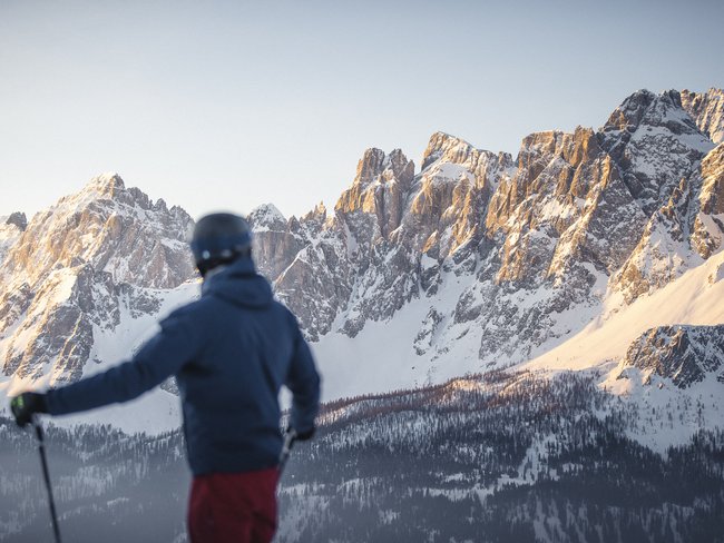 Urlaub im Hotel in den Dolomiten Skifahrer blickt auf schneebedeckte Berge bei Sonnenuntergang